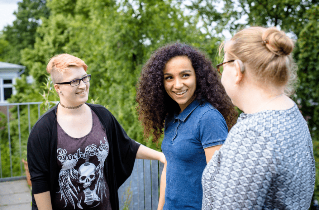 3 junge Menschen stehen zusammen und diskutieren